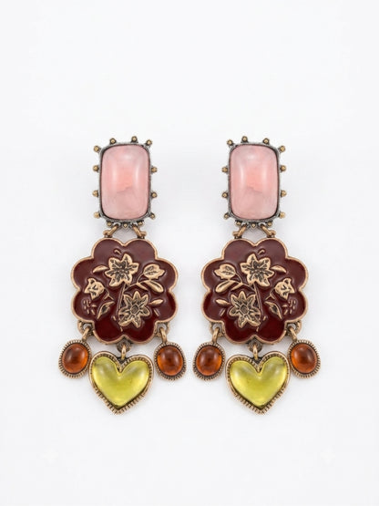 A pair of ornate drop earrings featuring a rectangular pink stone, a dark red floral enamel motif with gold-tone floral details, and dangling amber and yellow heart-shaped stones, set against a plain white background.
